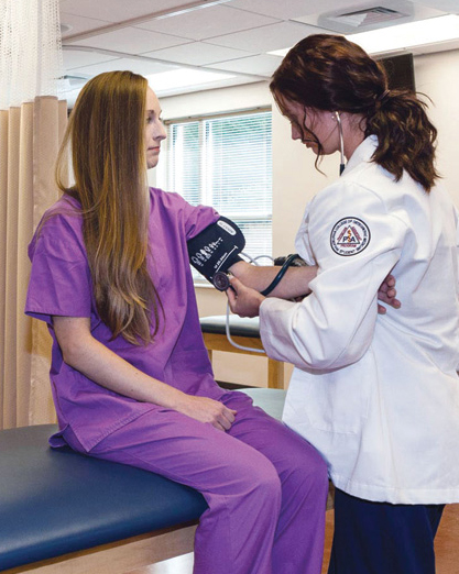 A PCOM physician assistant student practices taking blood pressure on a fellow student