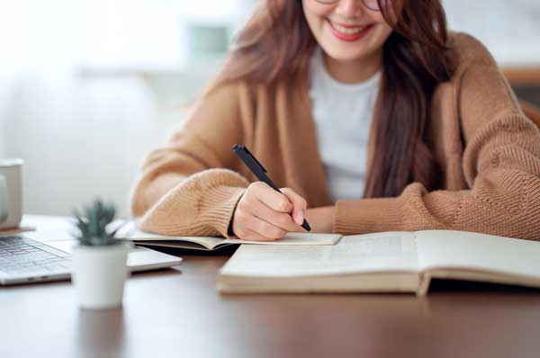 A female writes in a notebook.