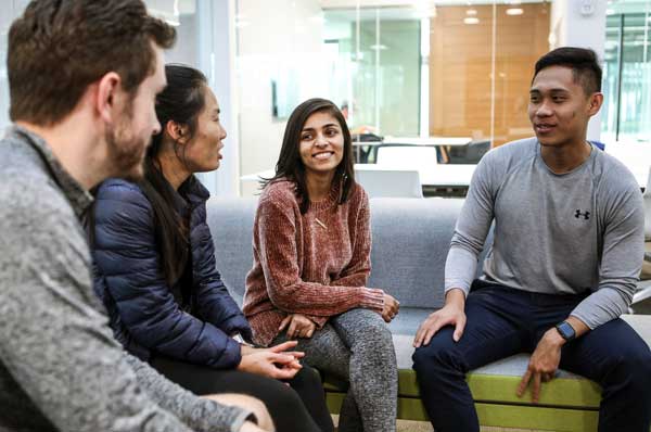 Students sit in a lounge smiling and discussing examples of positive psychology