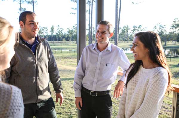 The success of positive psychology interventions can be examined at several levels. Here, a smiling male is standing outside with another smiling male and two smiling females. 