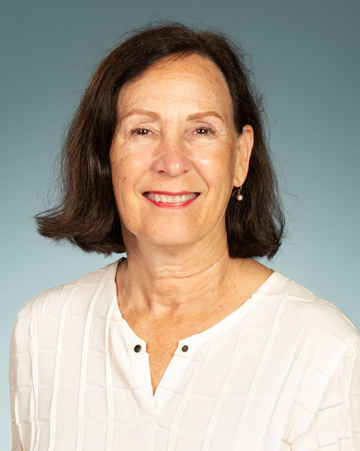 PCOM Chief Research and Science Officer Mindy George-Weinstein, PhD, smiling and wearing white lab coat