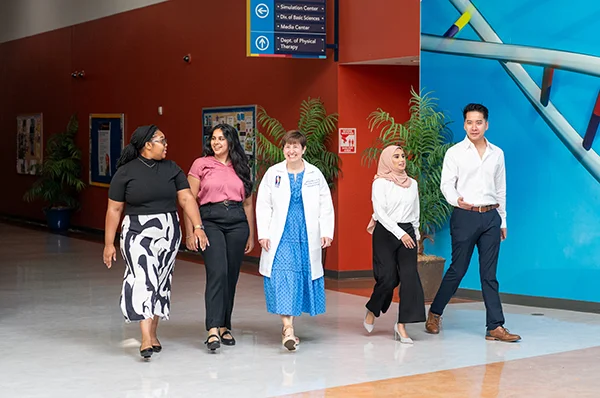 Admissions staff, faculty, current students and visiors walk and talk during a campus tour event