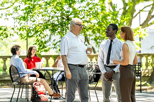 PCOM President Dr. Feldstein talks outside with students and visitors during a campus tour event
