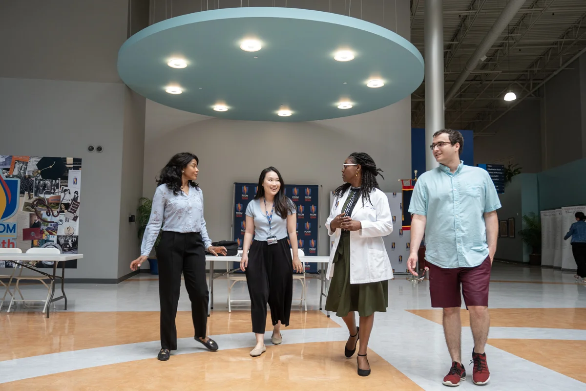 Students and faculty smiling and walking in PCOM Georgia's Atrium area