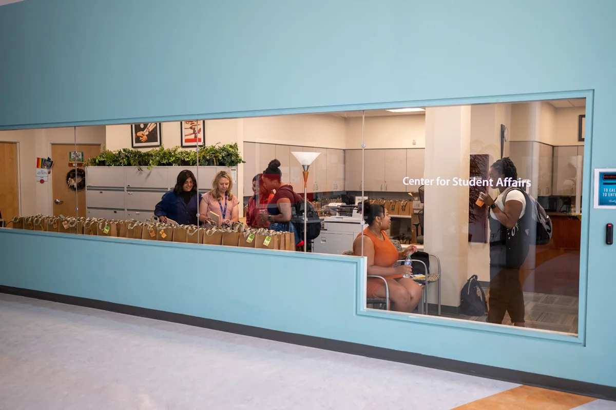 Looking through staff and students talking in a window of the Student Affairs Office at PCOM Georgia