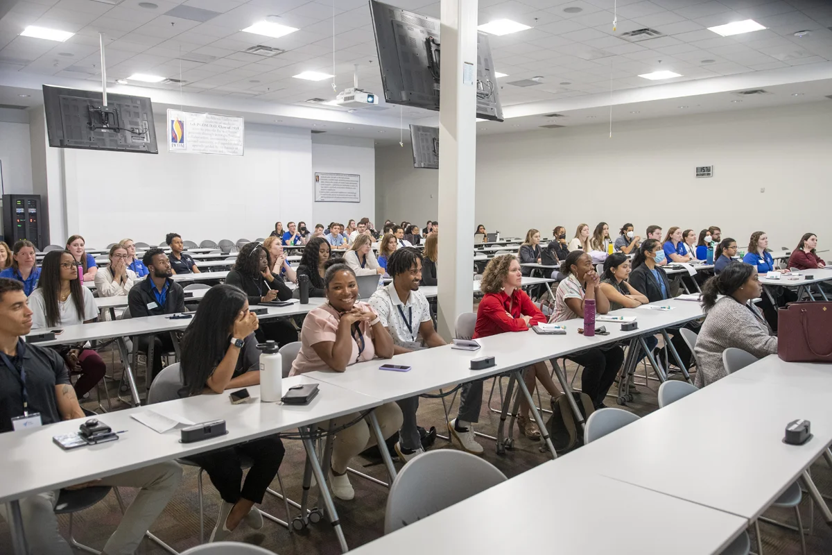 Students smiling and listening to a lecture at PCOM Georgia