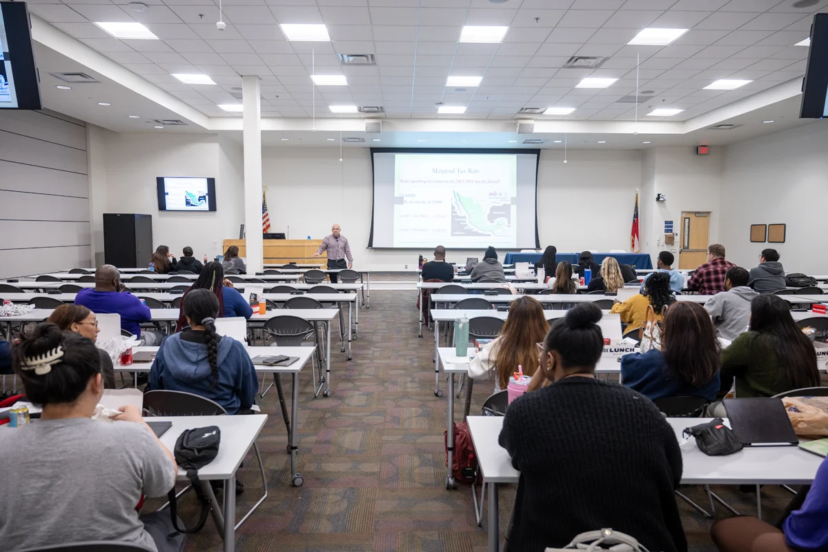 Students listening and taking notes in rows of tables and chairs during a class at PCOM Georgia