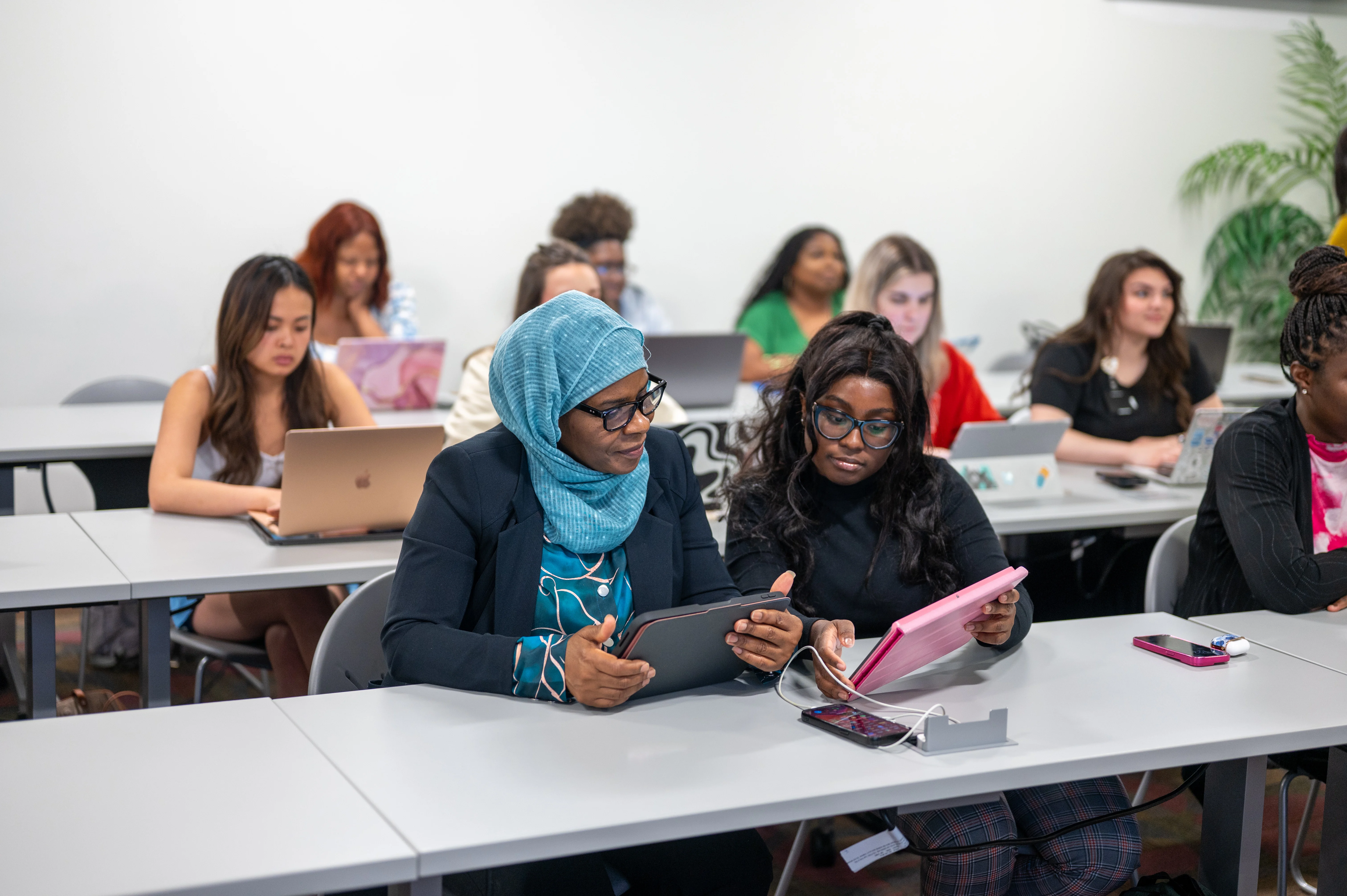 Students smiling as they use their tablets to take notes during a lecture at PCOM Georgia