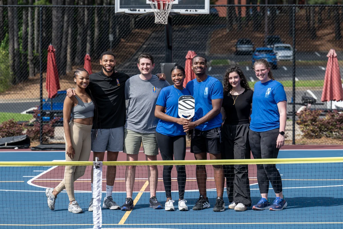 PCOM Georgia students smiling on the sports court holding pickleball paddles