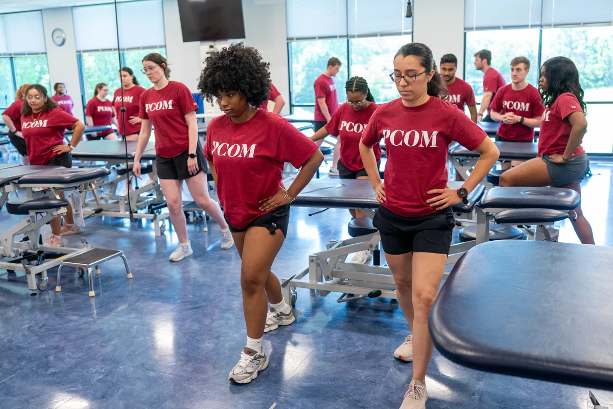 Physical therapy students perform stretches as a group in a classroom