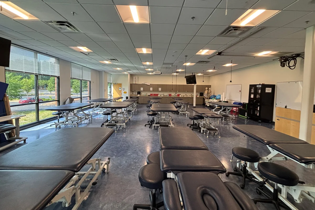 Wide shot of a Physical Therapy classroom with windows facing outside and exam tables