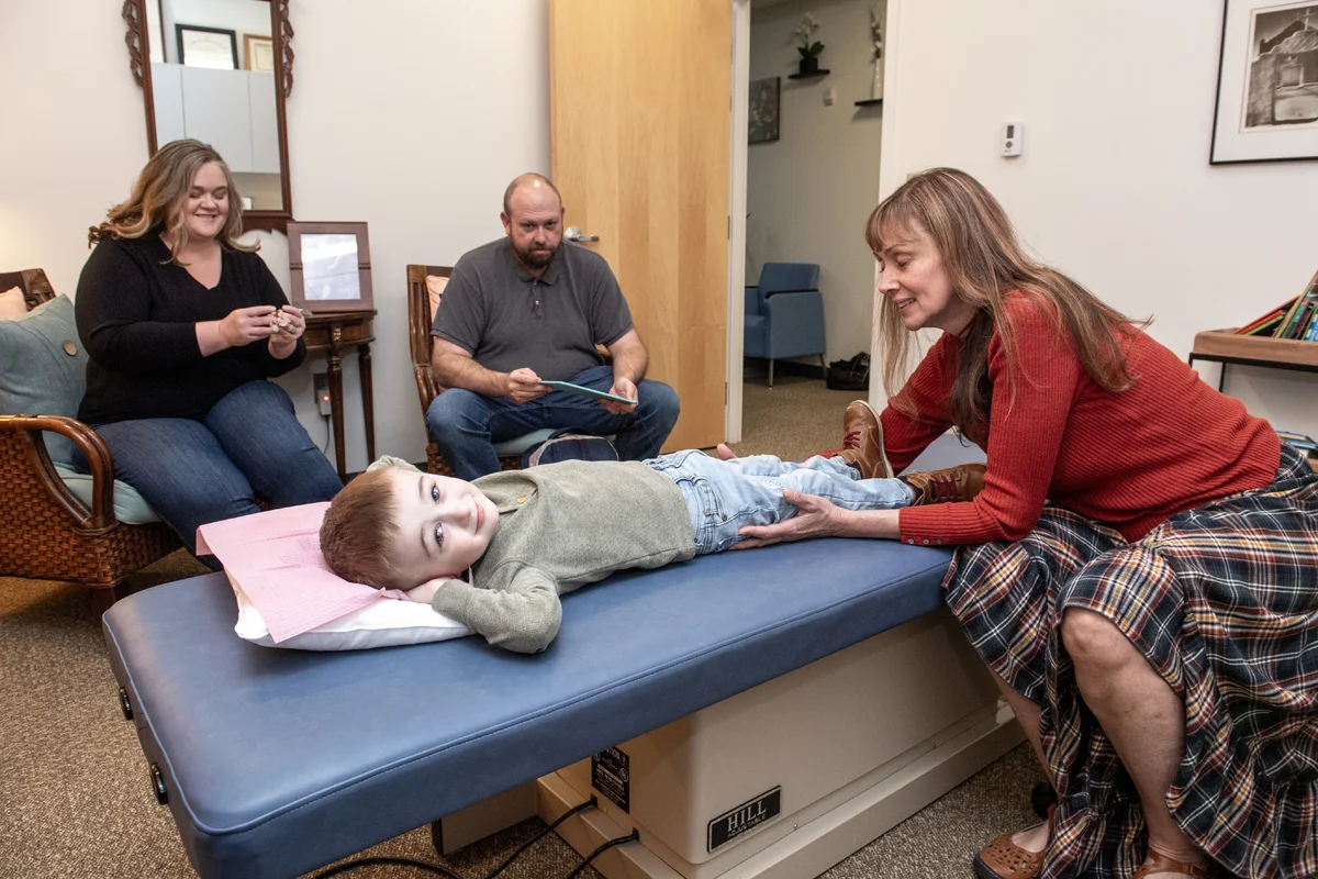 A child smiles while receiving OMM treatment from a GA OCC physician