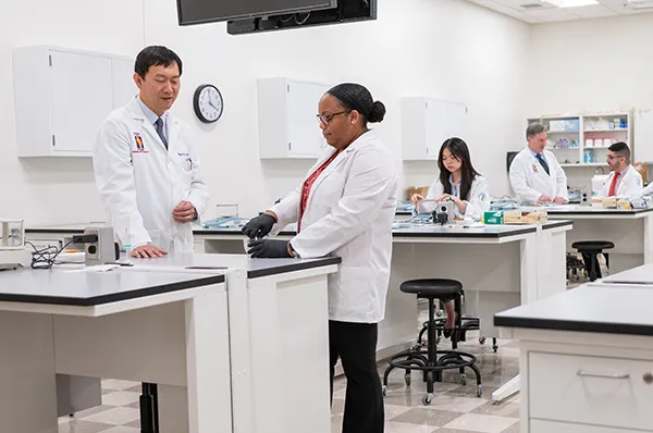 Pharmacy students interacting with faculty in a laboratory