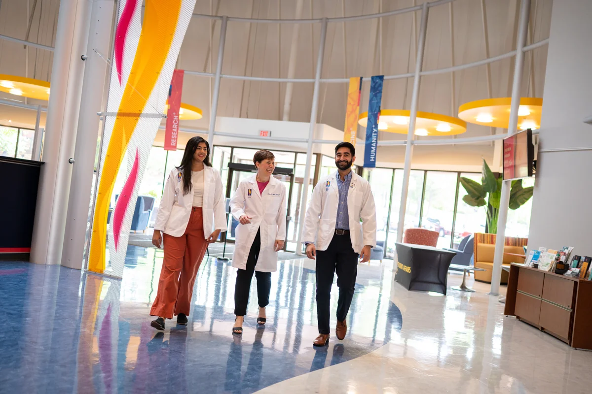 Dr. Mann and two students walk through the main lobby
