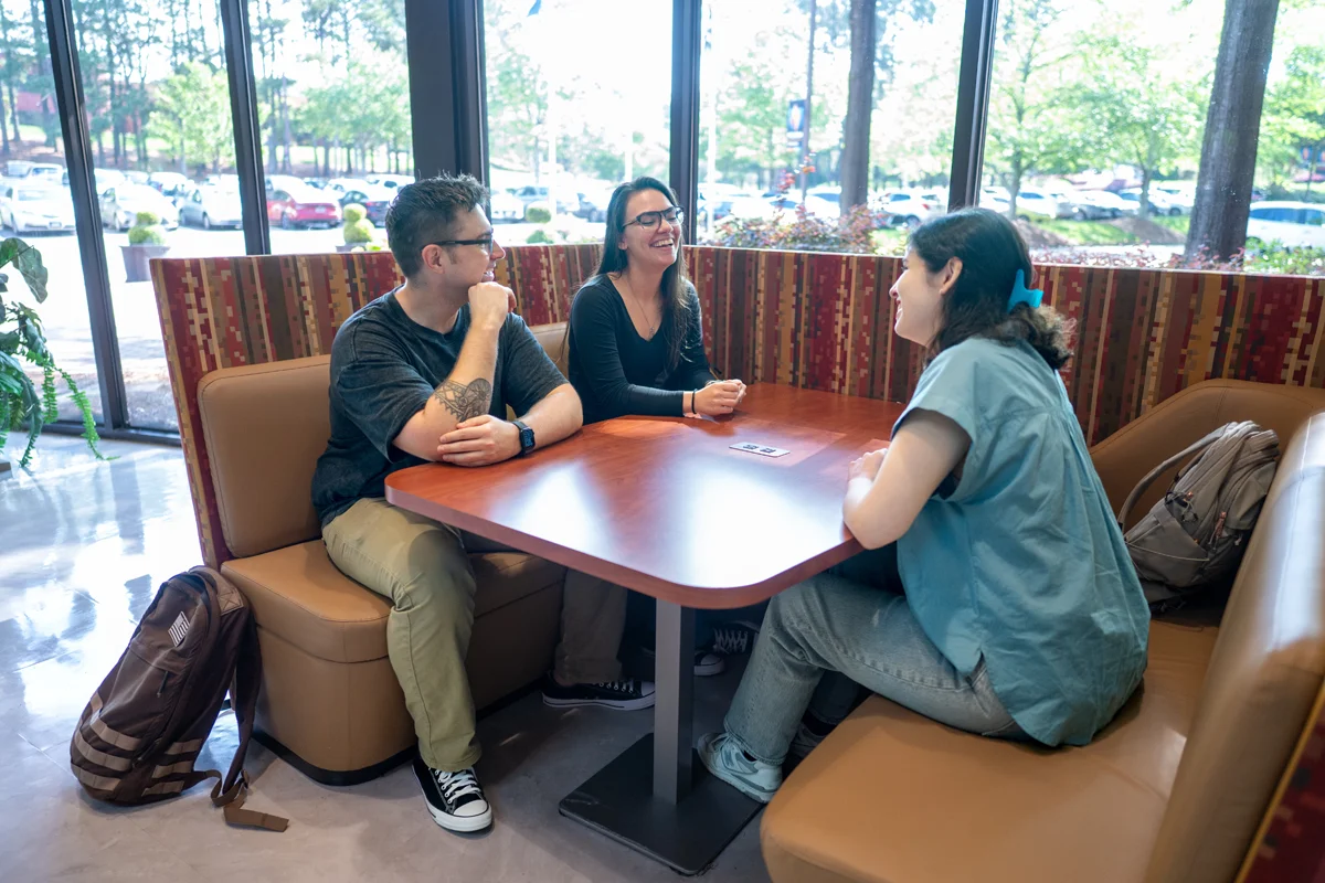 Students chatting at a table next to the front windows of PCOM Georgia's lobby