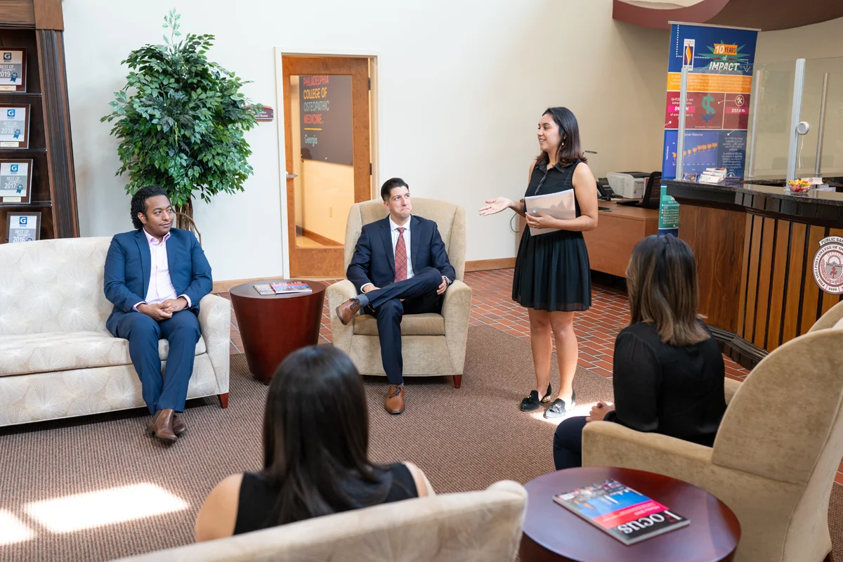 Staff and prospective students smile during a campus tour presentation in the Northlake building lobby