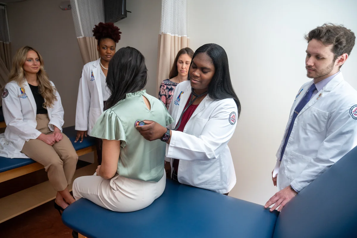 Physician assistant students smile while conducting a hands-on learning exercise