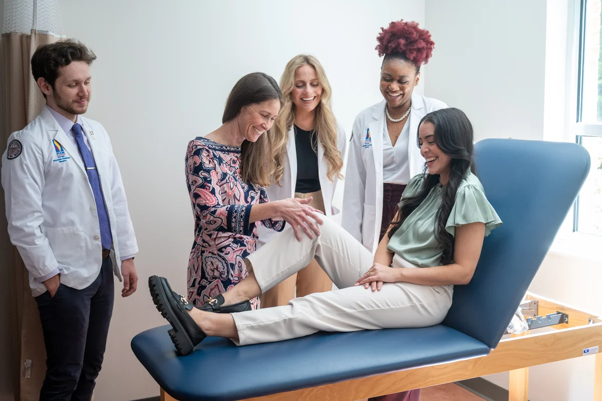 PA Studies students and faculty smile while practicing exam techniques