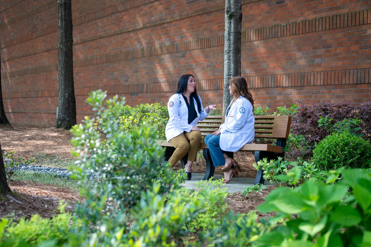 Students talking on a bench outside of PCOM Georgia's Old Peachtree building