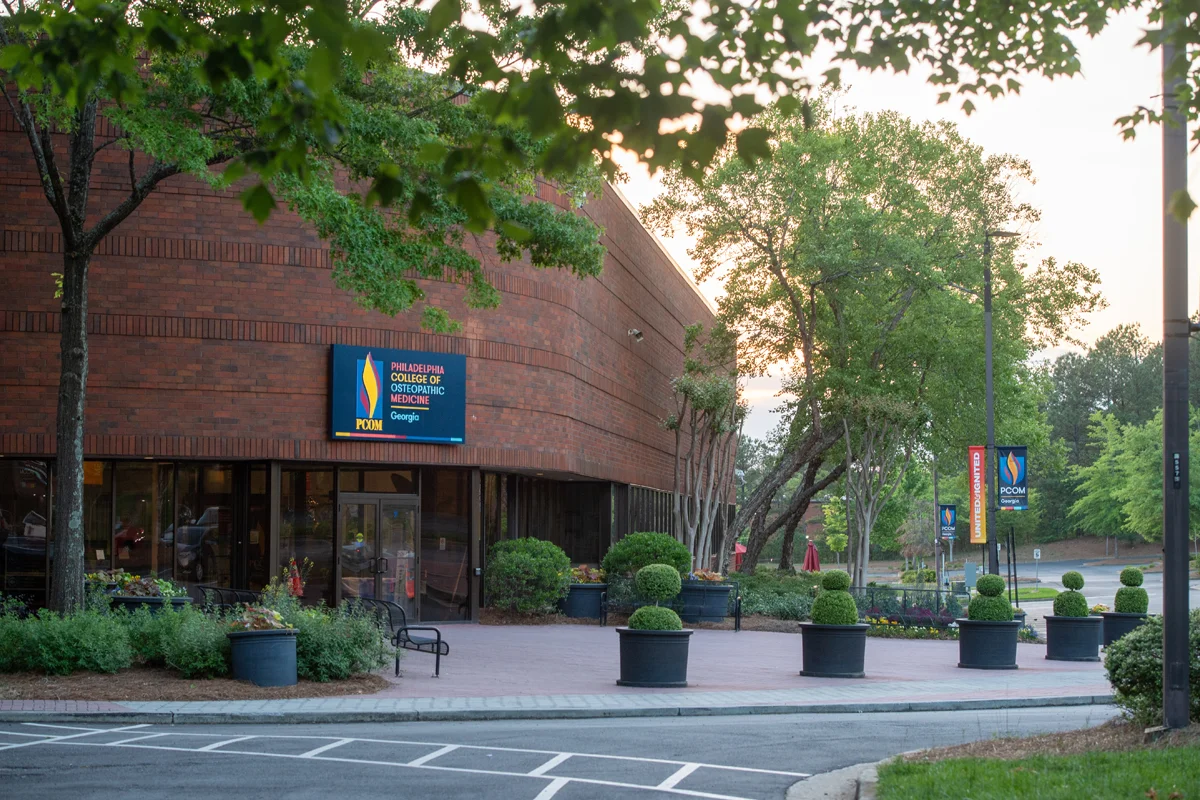 Front view of PCOM Georgia's main campus building and parking lot at dawn