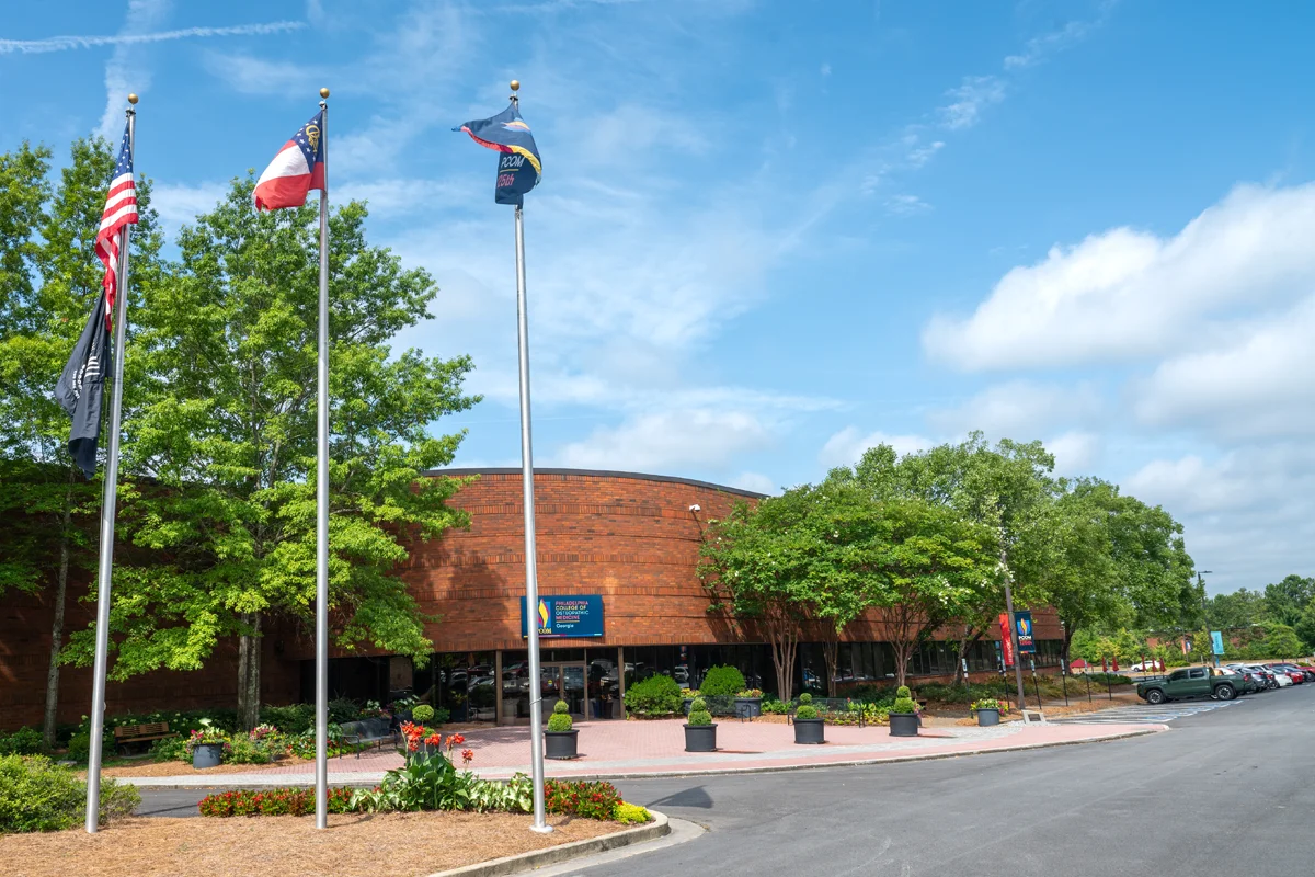 Wide view of the front doors and flag poles of PCOM Georgia's main campus building
