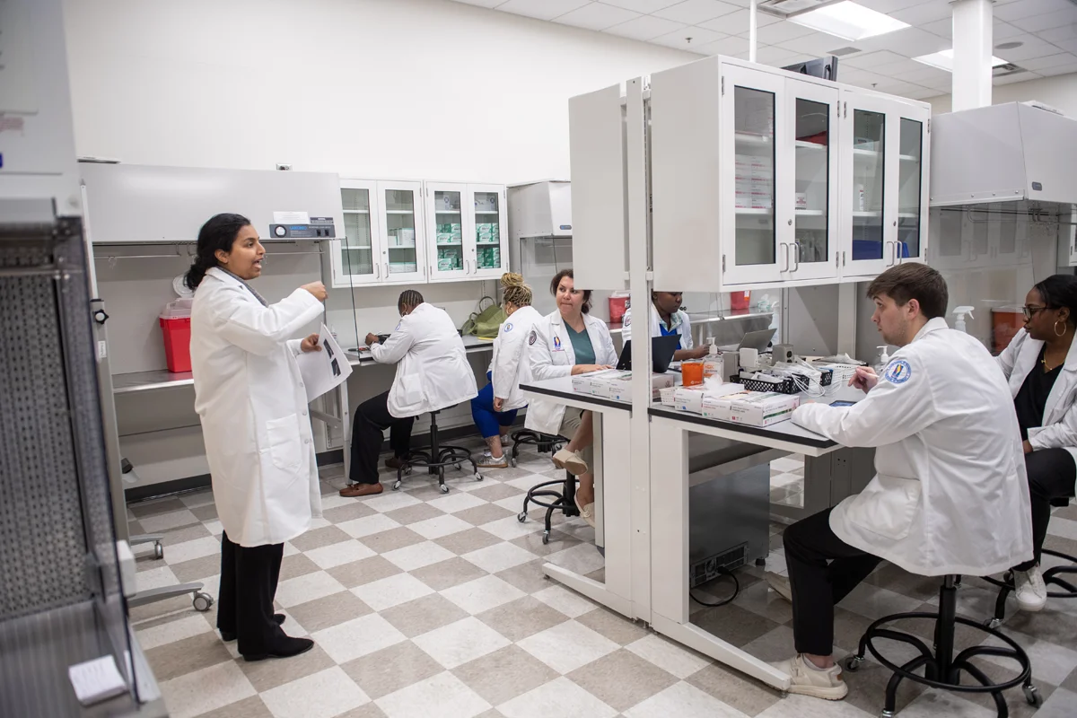 A PharmD faculty member instructs students in a pharmacy lab