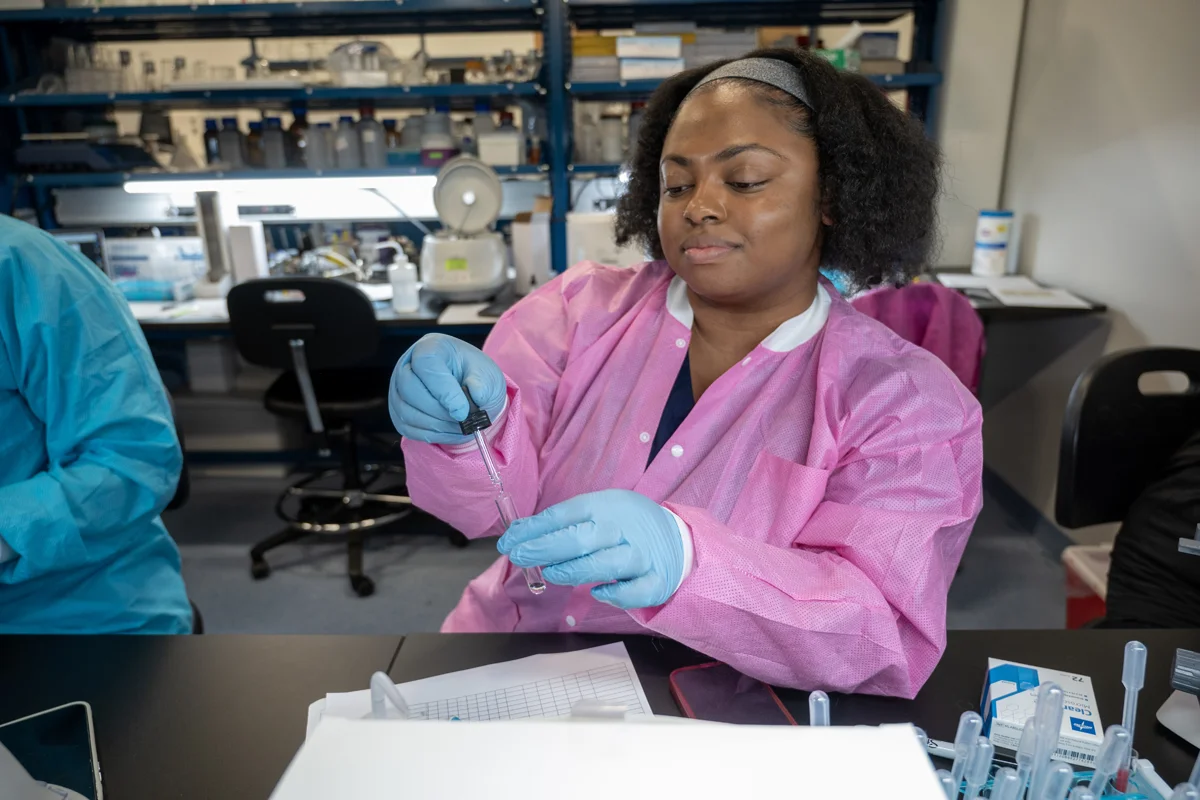 MLS student smiling as she mixes fluids in a PCOM research lab