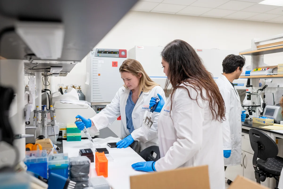 Students smiling while they work with equipment in a PCOM Georgia research lab