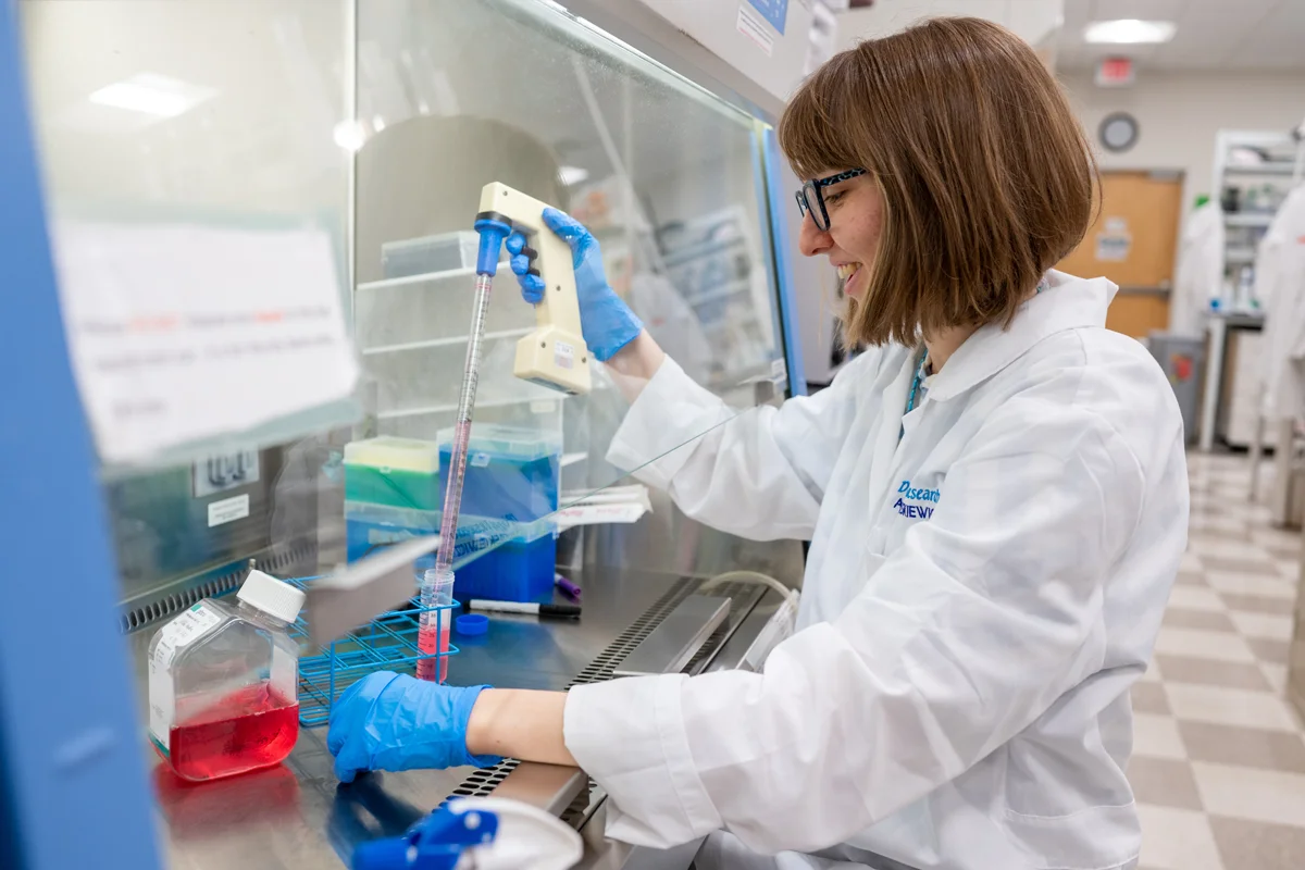 Student smiling while working with liquids in a lab at PCOM Georgia