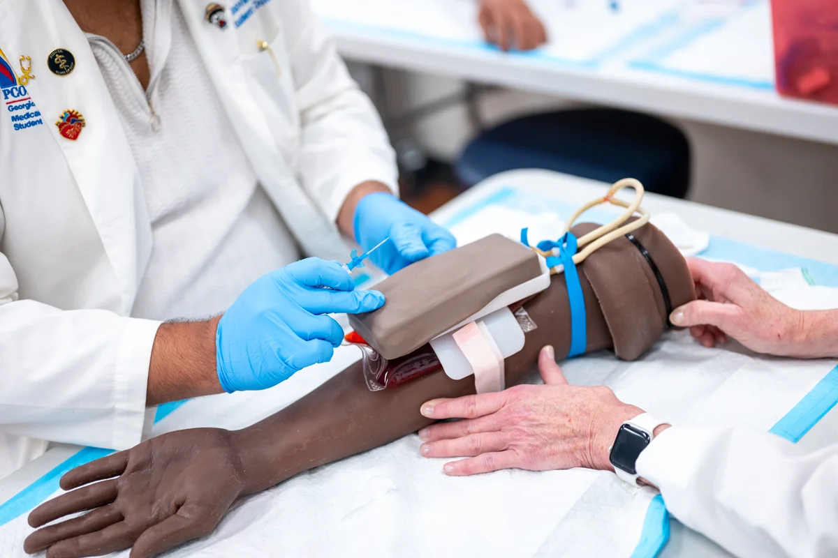 Students practicing techniques on an arm simulation station in the PCOM Georgia Sim Center