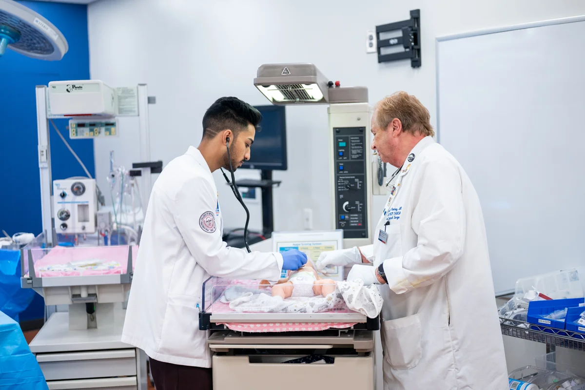 A male physcian and DO student tend to an infant sim mannequin