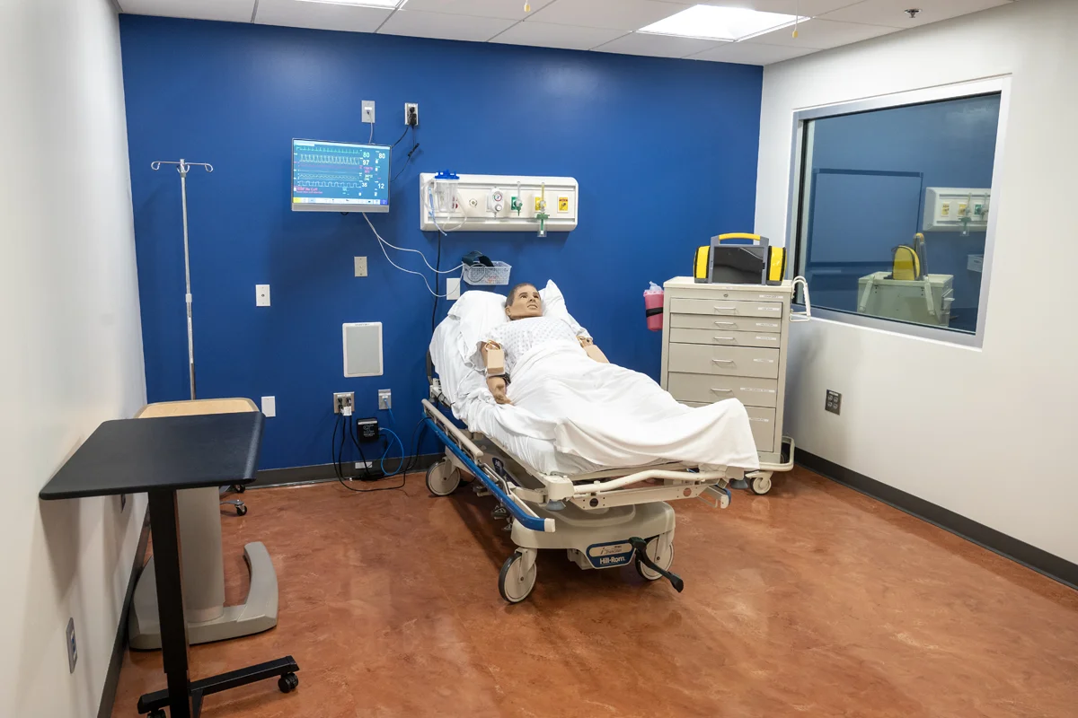 Simulation mannequin laying on a bed in an trauma room in the PCOM Georgia Sim Center