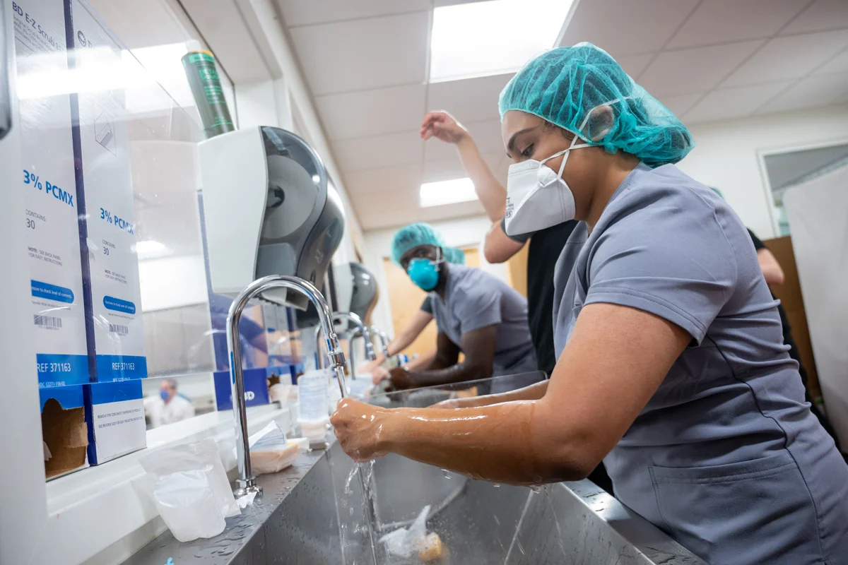 Students in PPE and face masks washing their hands in the Simulation Center