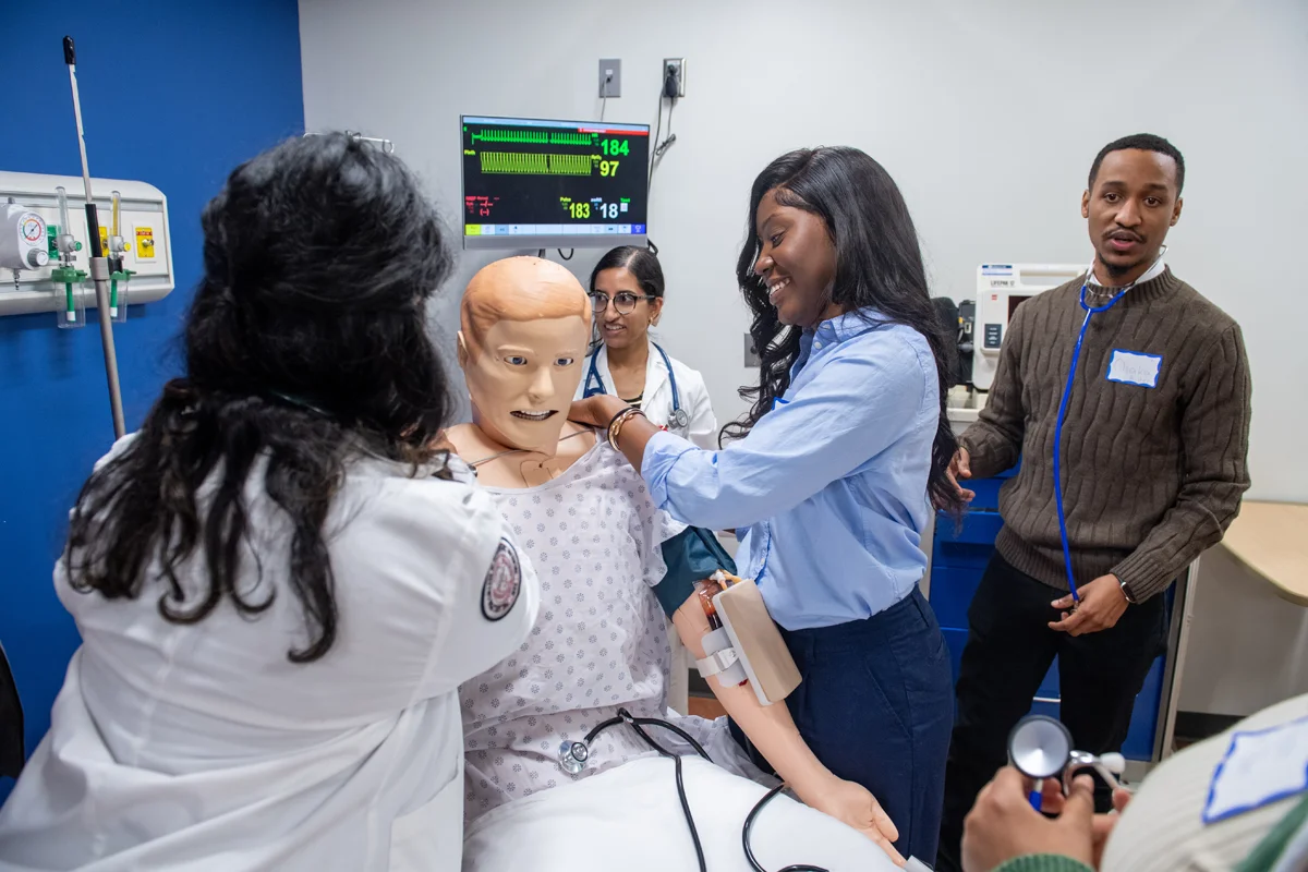 Students examine a mannequin on a hospital bed