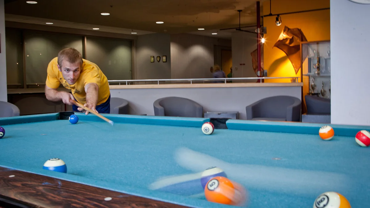 Student playing billiards in the PCOM Activities Center's game room