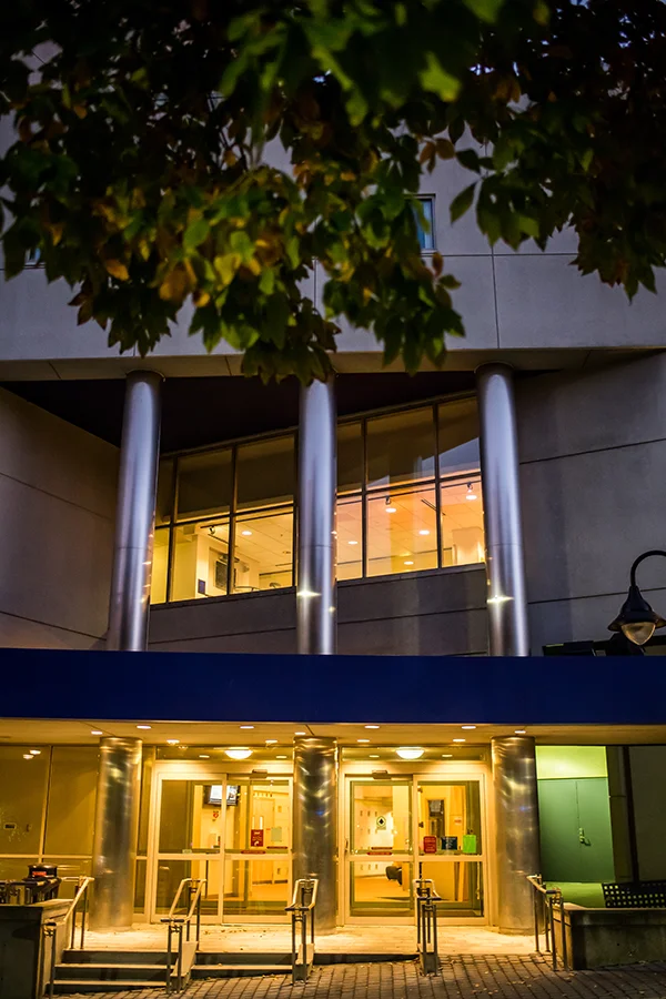Front view of the Activities Center front doors and building facade lit up at night