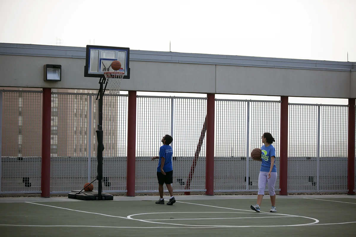 PCOM students shooting basketballs on the rooftop sports court of the Activities Center