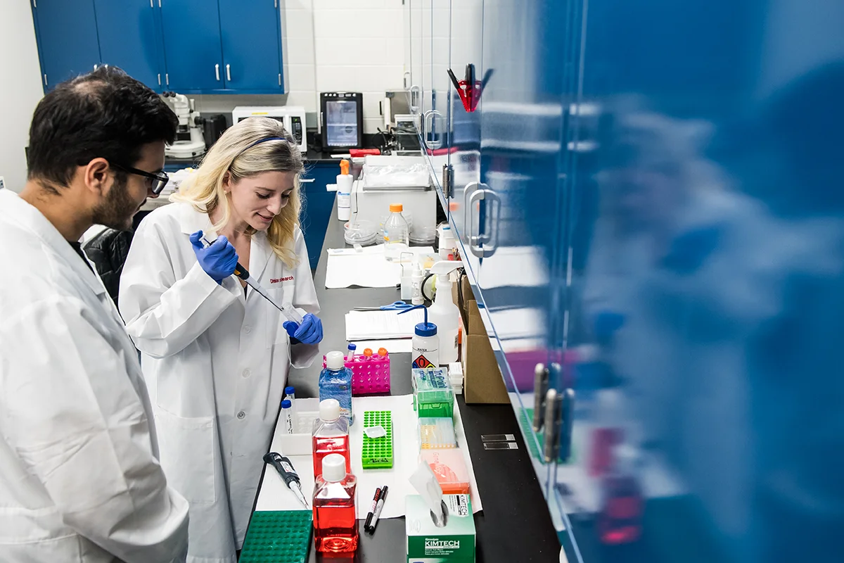 Students smiling as they handle fluids with instruments in the bioimaging laboratory