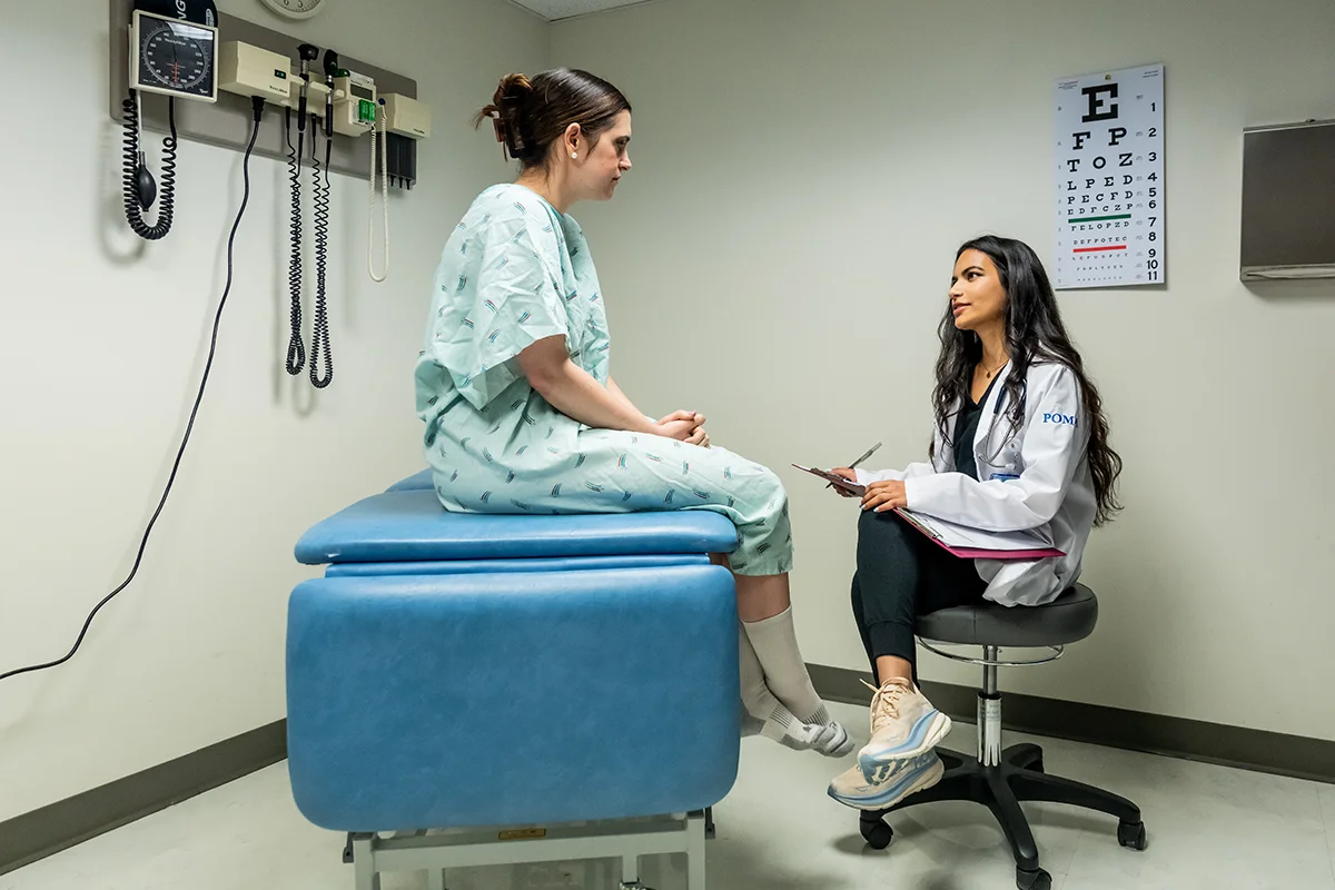 A med student talks to a patient actor in an exam room