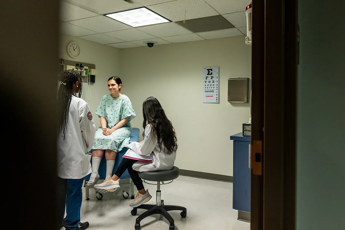 PCOM medical students conduct a simulated patient examination with a standardized patient actor in an exam room