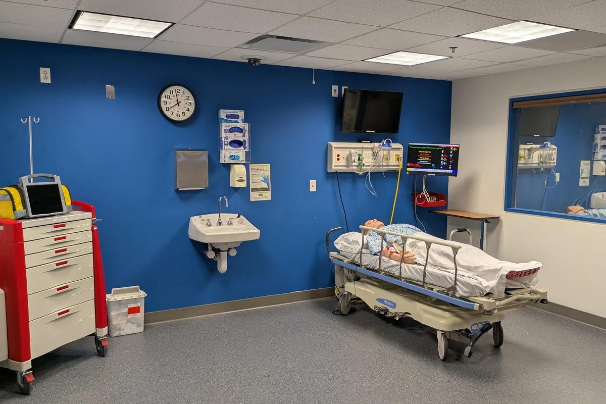 A corner of the Simulation Center's trauma room and simulation mannequin on a bed