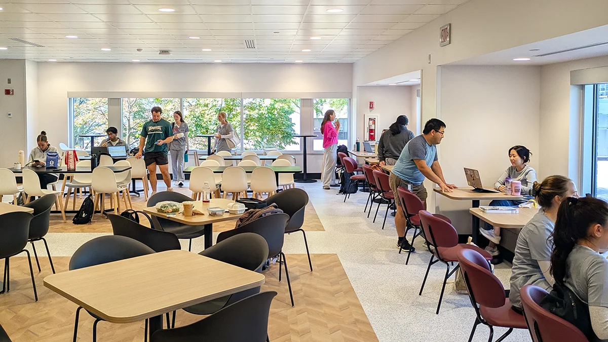 Students and staff eating and chatting during lunch hour in the Dining Commons' seating areas