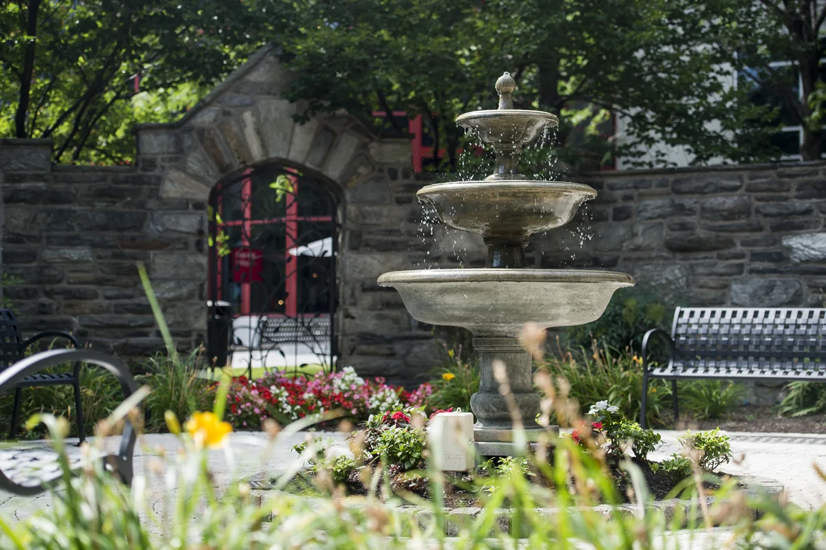 Yellow and red flowers in the landscaping beds besides the fountain in the Robert Gober, DO '78, Fountain and Donor Garden