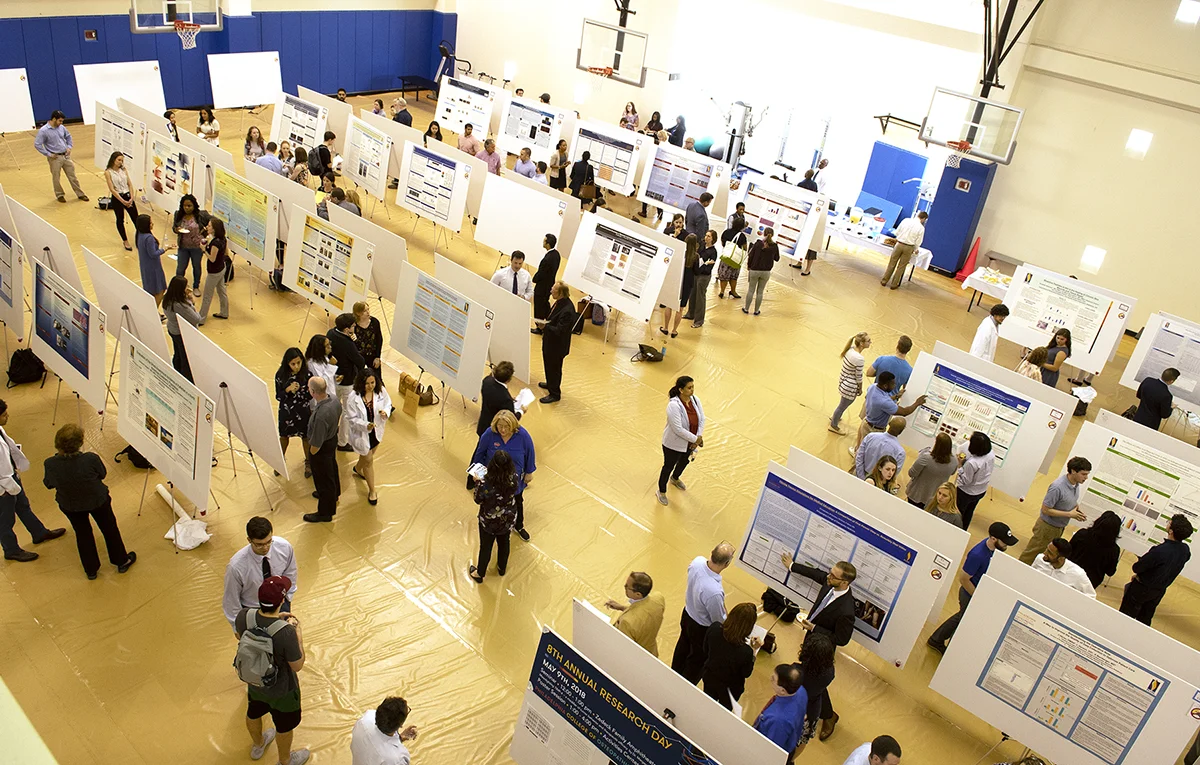 Aerial view of students, faculty and staff talking on the PCOM gym floor during the annual Research Day event