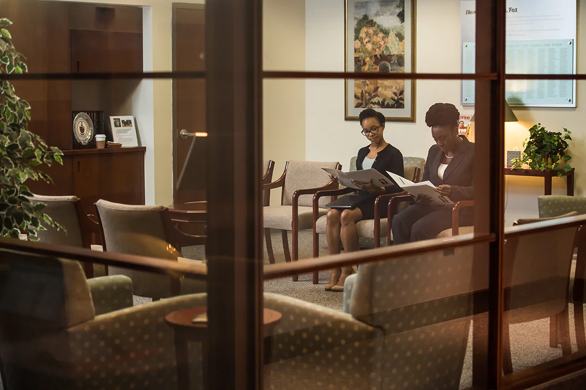 Two students read welcome materials in the PCOM Admissions Office
