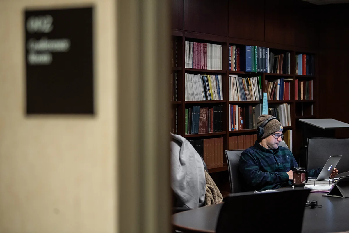 A Grad student studying on a laptop within a conference room at PCOM