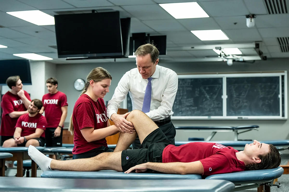 Students and faculty concentrating while practicing stretching techniques on a student