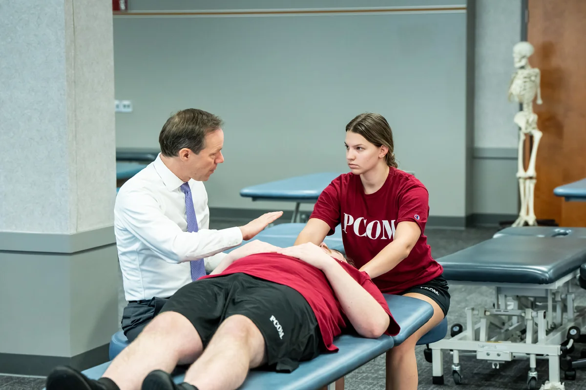 Student listening to a professor demo an OMM stretch on a fellow student