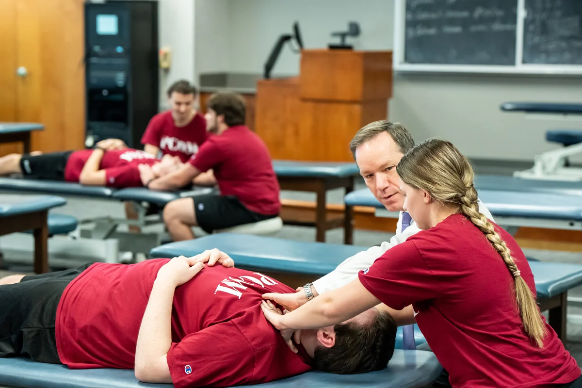 Wide view of PCOM students learning OMM in the laboratory classroom space