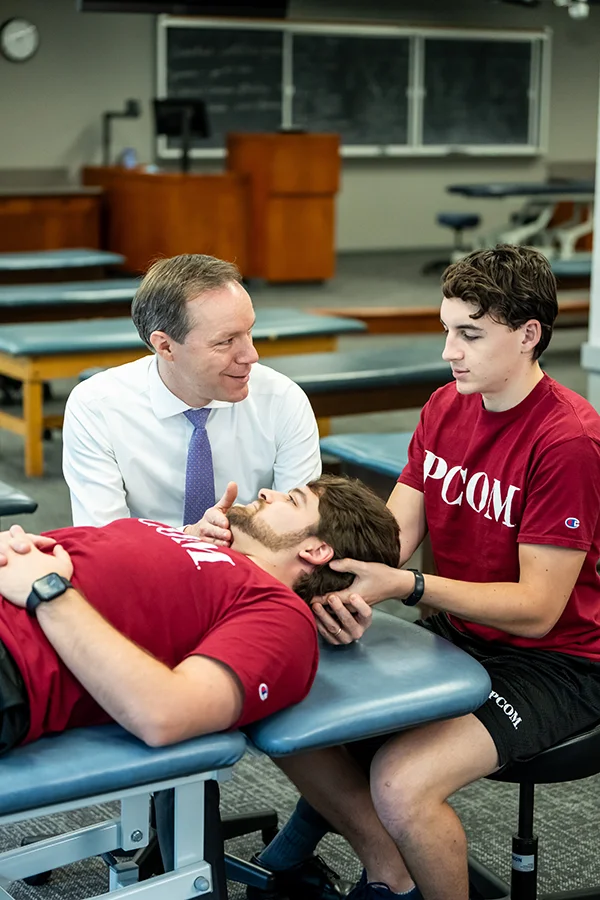 Vertical shot of a PCOM's Dr. Allison helping a student learn OMM principles